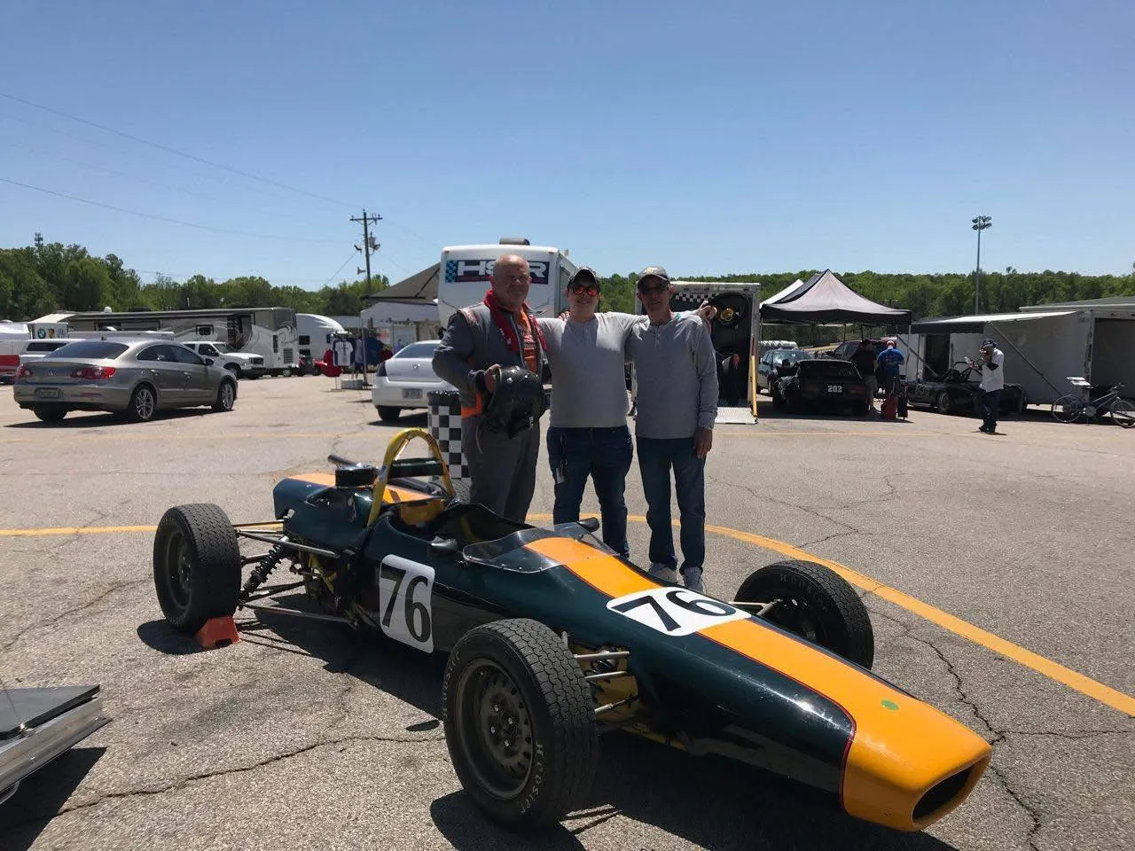 Sebastian with his uncle and his dad beside a vintage open-wheel race car
